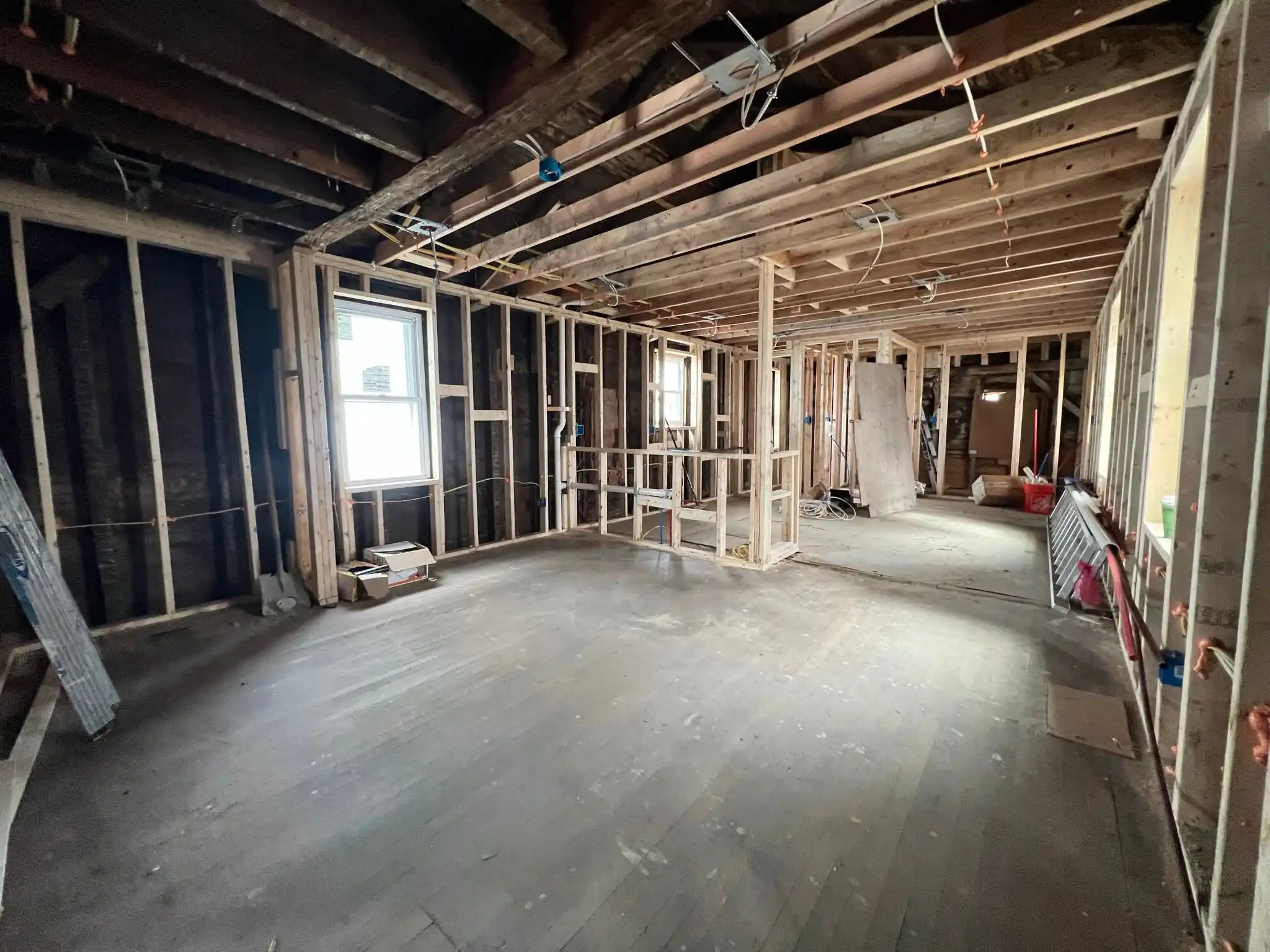 Contractor for new constructions in CT. Interior of a house under construction with exposed wooden framing, wiring, and tools.
