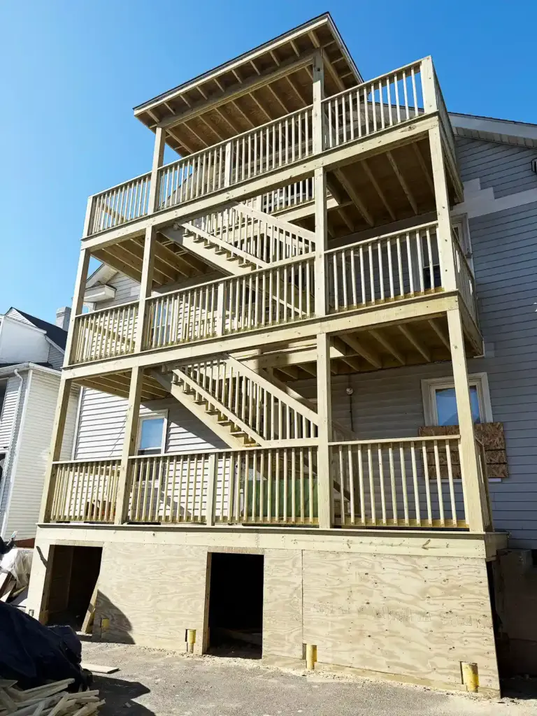 Deck installation contractor in CT. Multi‑level wooden deck under construction with railings, stairs, and an enclosed lower section.